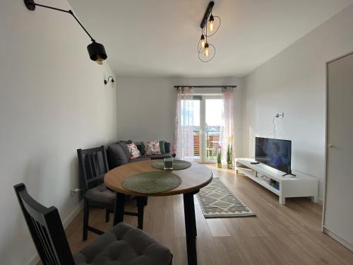 a living room with a table and a tv at Apartament Nad Stawem in Wadowice