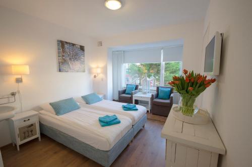 ein Schlafzimmer mit einem Bett und einer Vase aus Blumen auf einem Tisch in der Unterkunft Pension Oranje in Zandvoort