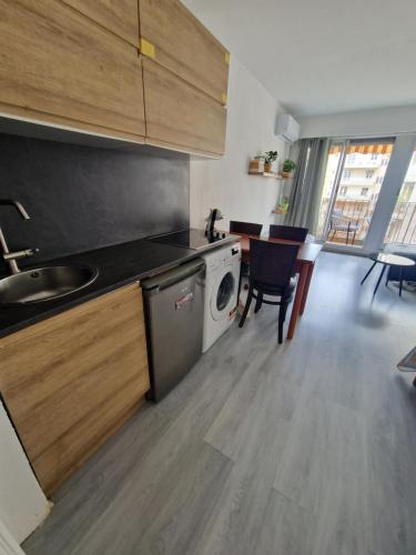 une cuisine avec une machine à laver et une table avec des chaises dans l'établissement Lory's home, à Nice