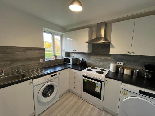 a kitchen with a stove and a washer and dryer at Cosy 2 Bedroom Apartment near City Centre in Manchester