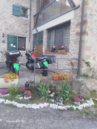 a motorcycle parked in front of a building with flowers at La Corte dei Celti La fonte in San Benedetto Del Querceto