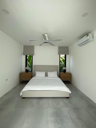 a white bedroom with a bed and a ceiling fan at LAILA Villas in Koh Samui 