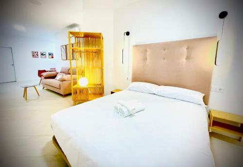 a bedroom with a large white bed and a couch at Apartamentos Guerrero in Merida