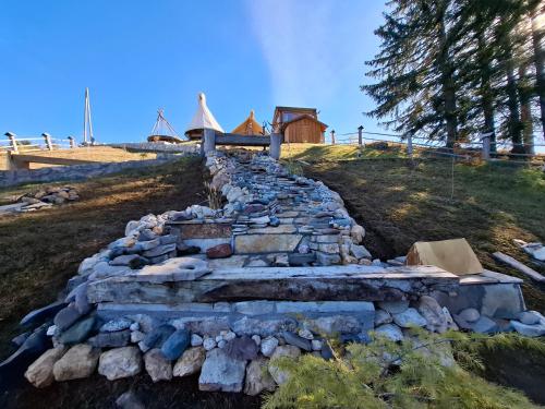 a stone wall on a hill with a house in the background at Guesthouse Planinarski dom Neviđen'o in Žabljak