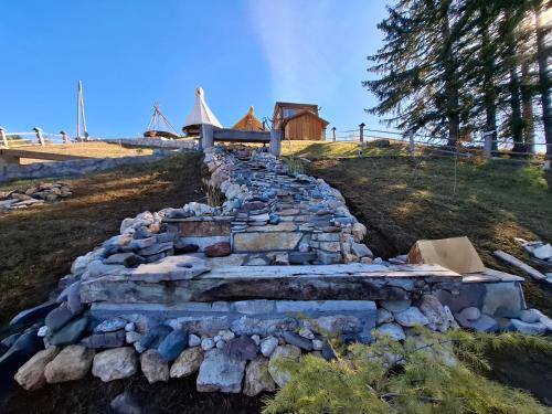 a stone wall on a hill with a house in the background at Guesthouse Planinarski dom Neviđen'o in Žabljak