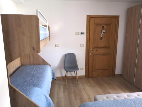 a bedroom with a bunk bed and a chair and a door at La Terrazzetta Val Comelico in Santo Stefano di Cadore