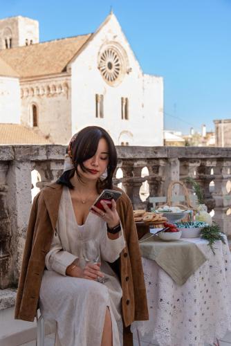 a woman sitting at a table looking at her cell phone at Casa Apuliae Bed & breakfast in Bitonto