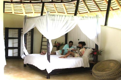 two people sitting on a bed in a bedroom at Las Nubes Resort in Savegre