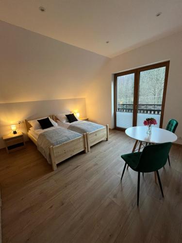 a bedroom with a bed and a table and a window at Malowany Las in Międzybrodzie Bialskie