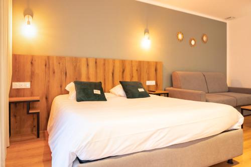a bedroom with a large white bed and a chair at Auberge les Oliviers in Lucciana