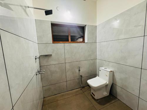 a bathroom with a toilet and a window at BougainVilla in Trivandrum