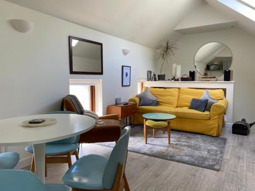 a living room with a yellow couch and a table at Beautiful renovated stone house for Dog friendly, Quayside location in Newport
