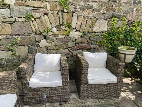 two wicker chairs sitting next to a stone wall at Beautiful renovated stone house for Dog friendly, Quayside location in Newport