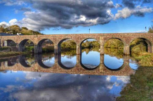 a bridge over a river with reflections in the water at Beautiful renovated stone house for Dog friendly, Quayside location in Newport