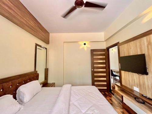 a bedroom with a bed and a flat screen tv at Lykke Suites- 2-min Drive to Colva Beach-By Goan Felicidade Hospitality PVT LTD in Colva