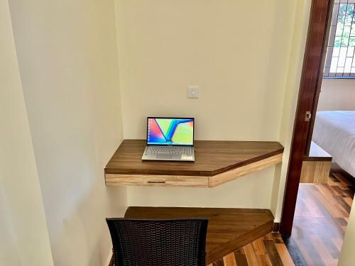 a laptop computer sitting on a wooden desk in a room at Lykke Suites- 2-min Drive to Colva Beach-By Goan Felicidade Hospitality PVT LTD in Colva