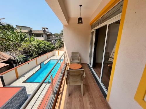a balcony with a table and chairs and a swimming pool at Lykke Suites- 2-min Drive to Colva Beach-By Goan Felicidade Hospitality PVT LTD in Colva