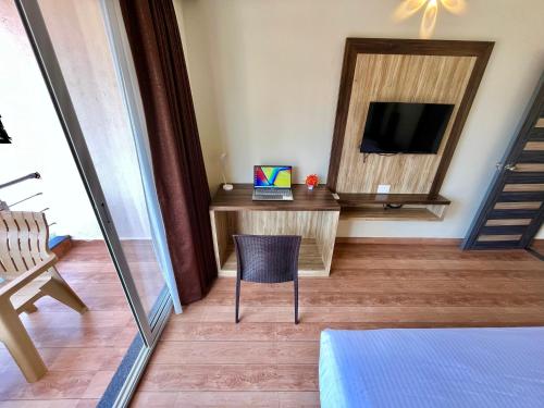 a room with a tv and a chair and a mirror at Lykke Suites- 2-min Drive to Colva Beach-By Goan Felicidade Hospitality PVT LTD in Colva
