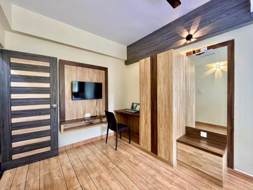 a room with a chair and a desk and a television at Lykke Suites- 2-min Drive to Colva Beach-By Goan Felicidade Hospitality PVT LTD in Colva