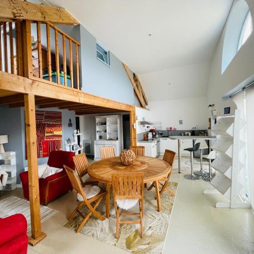 Il dispose d'une cuisine et d'un salon avec une table et des chaises en bois. dans l'établissement T4 spacieux au-dessus d'un centre équestre, proche bord de mer, à Larmor-Plage