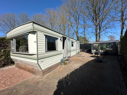 a white tiny house sitting on a patio at Stacaravan 130 De Tien Heugten in Schoonloo