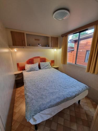 a bedroom with a bed with a blue comforter and a window at Mobile Home Emma in Lido di Dante