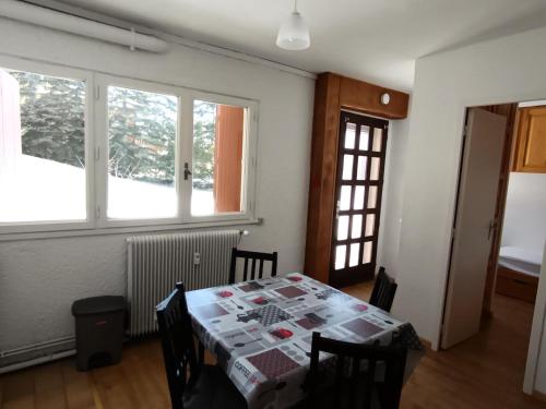 une salle à manger avec une table et deux fenêtres dans l'établissement Résidence Melezes A - Appartement 4 personnes en rez-de-jardin MAE-1334, à Montgenèvre