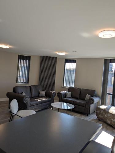 a living room with couches and tables and windows at London Heathrow Apartment - West Drayton in Yiewsley