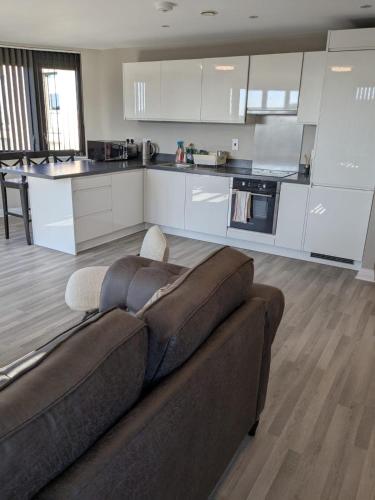 a living room with a couch and a kitchen at London Heathrow Apartment - West Drayton in Yiewsley
