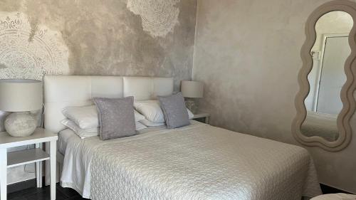 a bedroom with a white bed and a mirror at Borgo di Santa Barbara in Santa Domenica