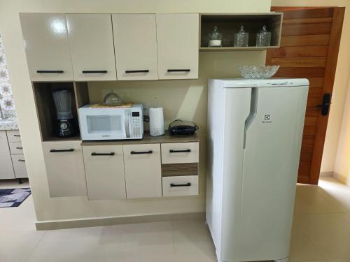 a kitchen with a white refrigerator and a microwave at Casa Vista da Pedra in Domingos Martins