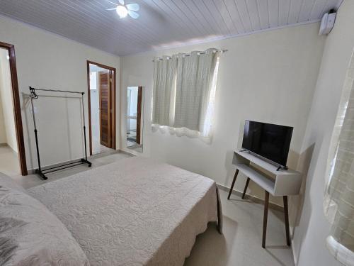 a white bedroom with a bed and a tv at Casa Vista da Pedra in Domingos Martins