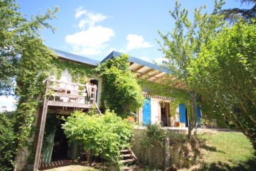 une femme assise sur une terrasse couverte d'une maison dans l'établissement L'Abeille Vie, à Tréziers