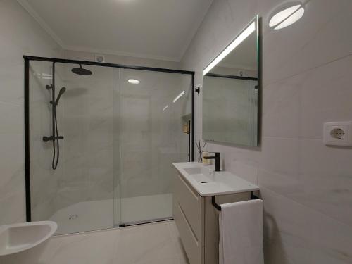 een witte badkamer met douche en wastafel bij Beach & Surf in Ribeira Grande