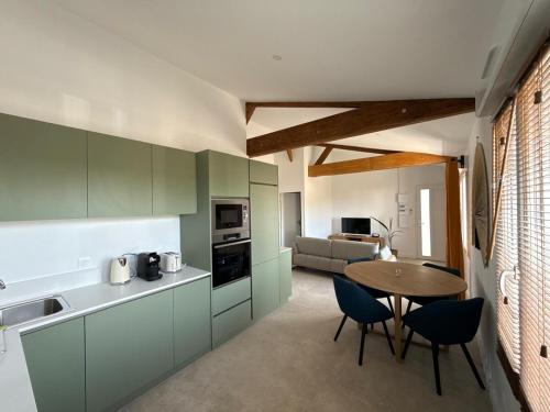 a kitchen with green cabinets and a table and chairs at Appartement cosy et élégant in Ambarès-et-Lagrave