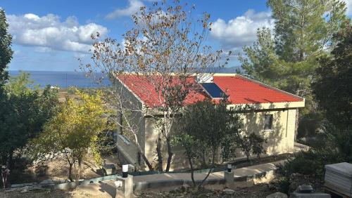 a small house with a red roof and the ocean at Philip's Akamas Retreat in Neo Chorio