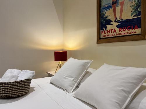 a bedroom with a bed with white pillows and a poster at Boutique Hotel Casa Grande, Tropical Journey, Suite familiar de 2 dormitorios in Santo Domingo