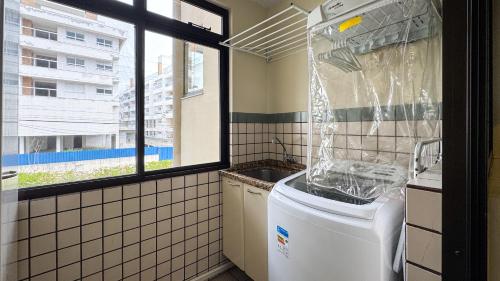 a washing machine in a bathroom with a window at Apto Cond. Porto Ventura 3 quartos in Florianópolis