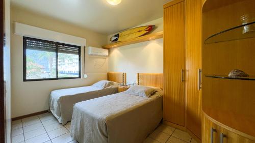 a room with two beds and a window with a surfboard at Apto Cond. Porto Ventura 3 quartos in Florianópolis