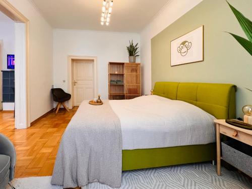 a bedroom with a large bed with a green headboard at SERVUS HOMES - Friends & Family in Vienna