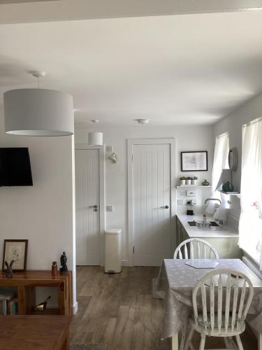 a living room with a table and a kitchen at Cottage in Mid Calder Village near Edinburgh in Mid Calder
