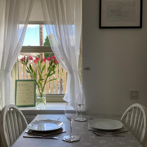 a table with two wine glasses and a window at Cottage in Mid Calder Village near Edinburgh in Mid Calder