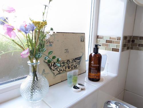 a window sill with a vase of flowers and a bottle of alcohol at Ty Collective - Near Town Centre in Dowlais