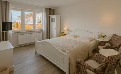 a bedroom with a large white bed and two chairs at Lodge am Meer in Glücksburg