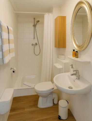 a white bathroom with a toilet and a sink at Lodge am Meer in Glücksburg
