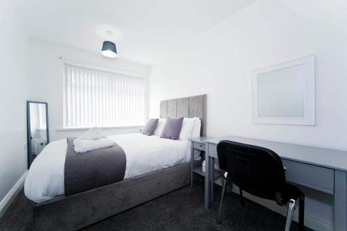 a bedroom with a bed and a desk with a chair at Belmont Budget Apartment in Stockton-on-Tees