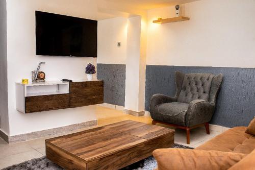 a living room with a couch and a chair and a tv at Lovek Condos in Kumasi