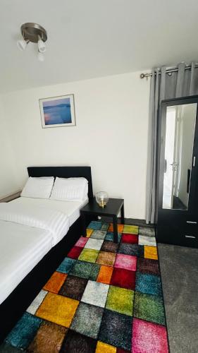 a room with two beds and a colorful rug at Cosy and Comfy Deluxe Entire Apartment in London