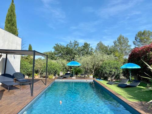 une piscine avec des chaises et des parasols dans l'arrière-cour dans l'établissement Athena, à Lorgues