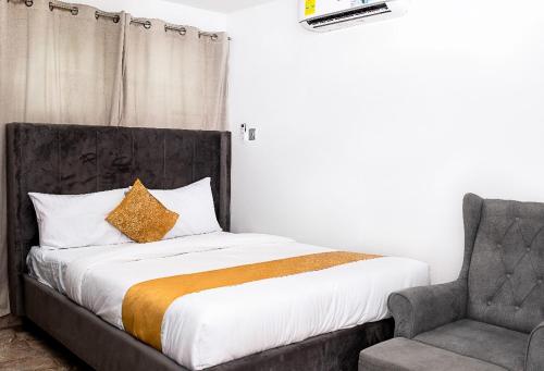 a bed and a chair in a room at Lovek Condos in Kumasi